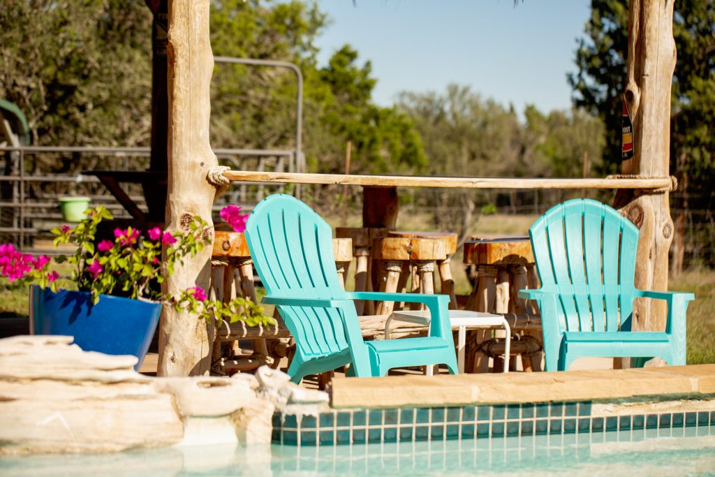 Two Adirondack chairs beside a sparkling pool at a vacation rental, perfect for relaxing and enjoying the sun.