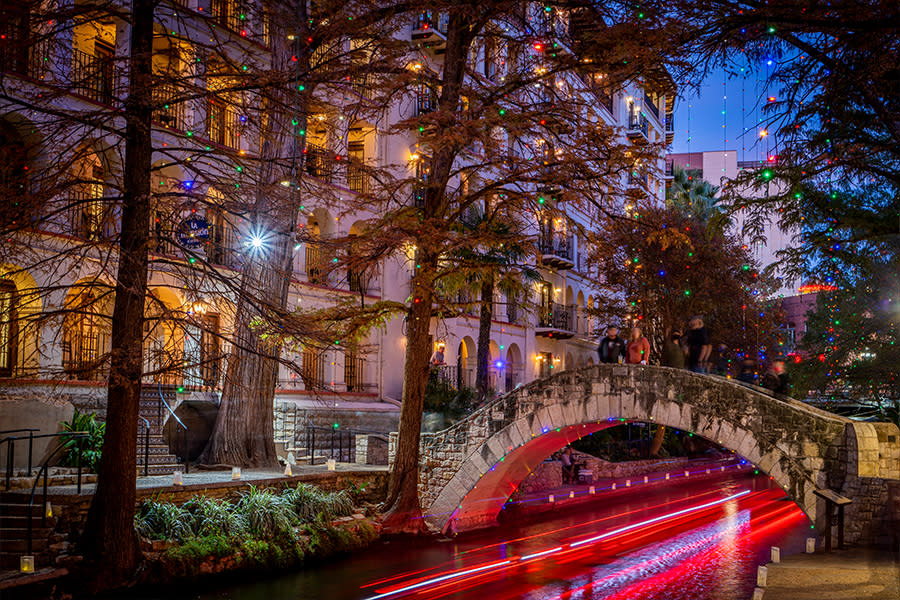 San Antonio River Walk at night illuminated with Christmas lights, reflecting on the river and creating a festive holiday atmosphere.