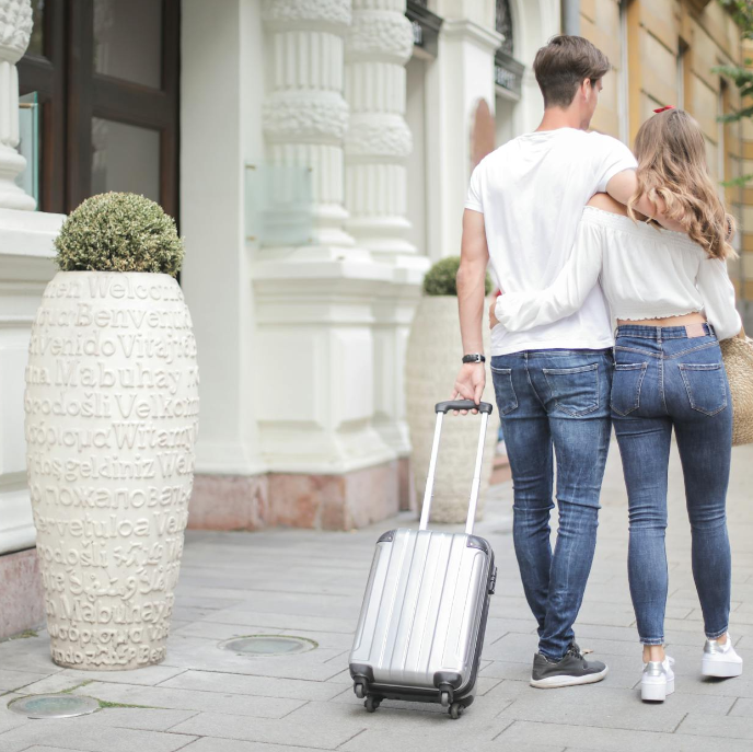 Tourists walking with luggage in a city neighborhood, representing year-round Airbnb demand in San Antonio