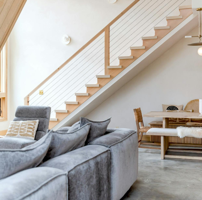 Modern condo interior with open living area, staircase, and dining space, ideal for a professionally managed short-term rental