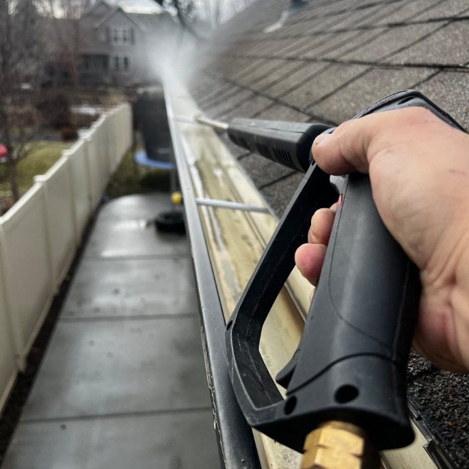 Cleaning gutters with a pressure washer during Spring Vacation Rental Preparations to prevent storm damage
