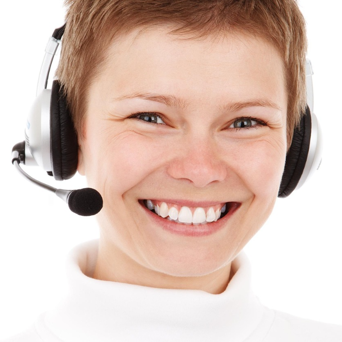 Friendly customer service agent with headset smiling directly at the camera.