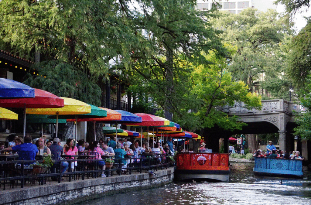 San Antonio River Walk with outdoor restaurants and a Rio San Antonio boat cruise, showcasing dining and sightseeing along the river.