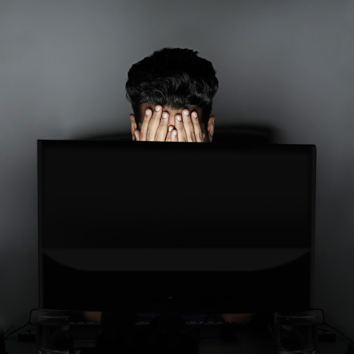 Frustrated vacation rental owner covering face behind a computer screen, overwhelmed by self-management tasks.
