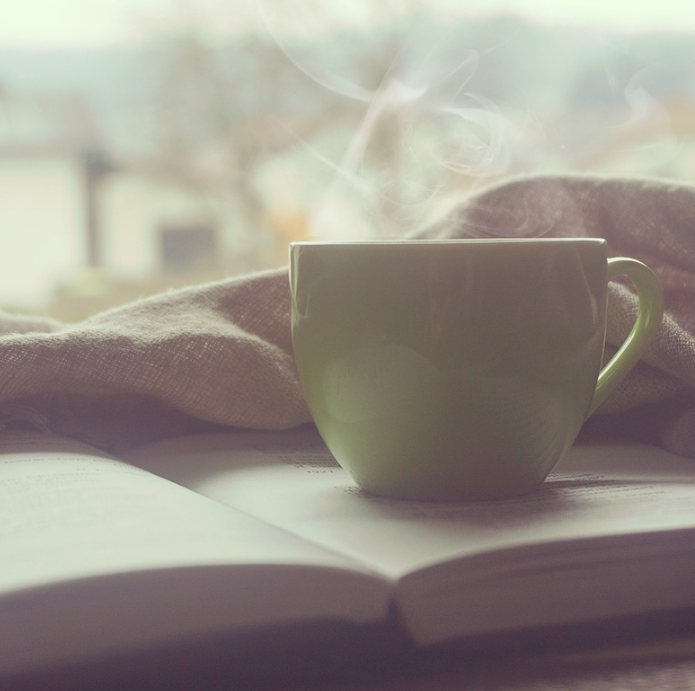Steaming cup of coffee on an open book, symbolizing peace and relaxation for vacation rental owners using professional property management.