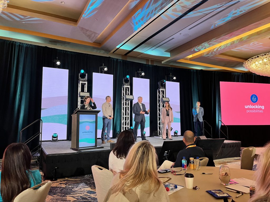 Leaders from iTrip, Inhabit, and the Independent Association of iTrip Franchisees on the main stage at the iTrip Summit, addressing attendees.